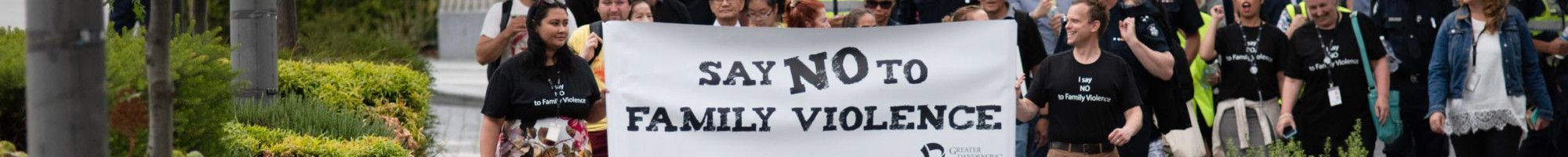 A crowd walks behind the Walk Against Family Violence banner