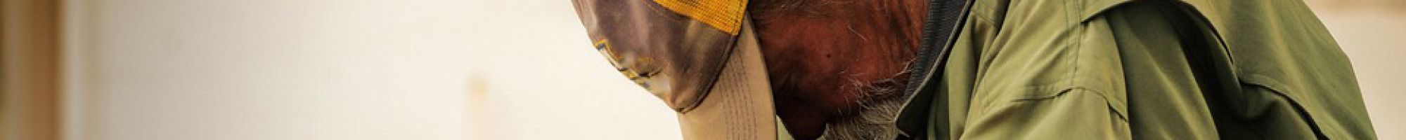 a person with their head down wearing very worn clothing