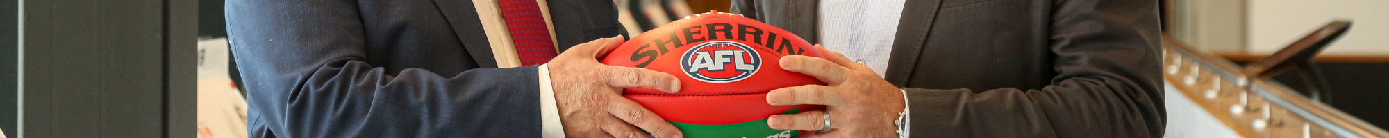 Mayor Cr Jim Memeti shaking hands with St Kilda Football Club Chief Operating Officer Simon Lethlean while holding a football