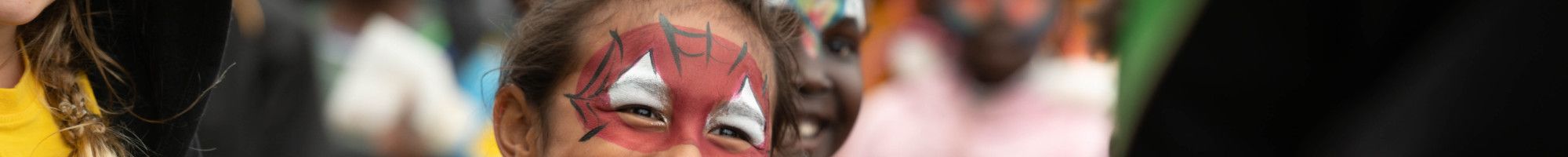 A laughing child with face painted like spiderman
