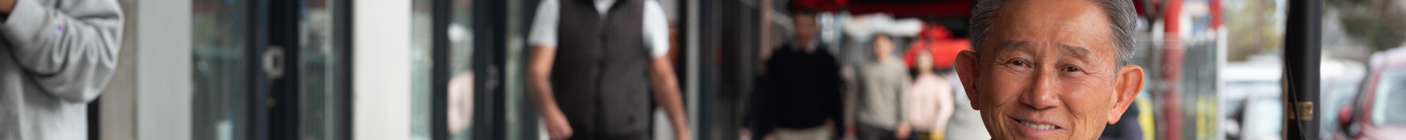 Councillor Richard Lim sitting on street furniture in Springvale