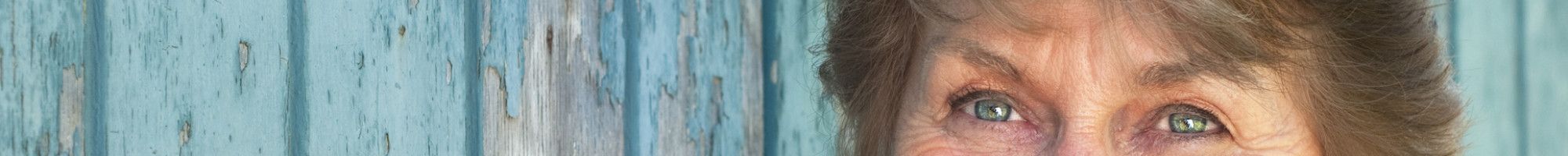 smiling senior woman smiling in front of a wooden wall
