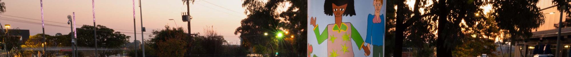 Seating and a light box in a public space decorated with colourful paintings of people