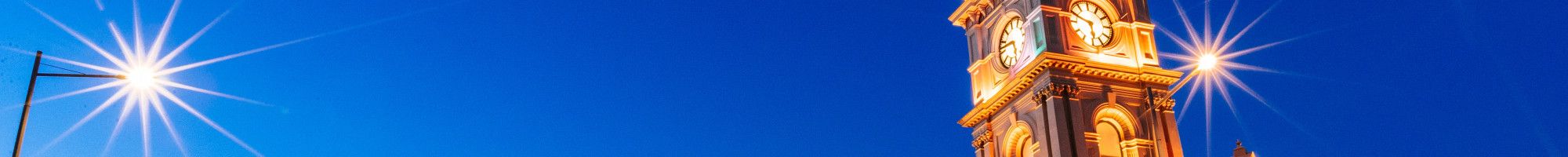 Heritage building with a clocktower lit up at dusk.