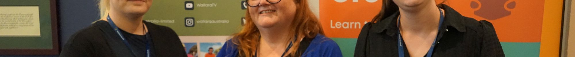 Three people standing in front of some banners.