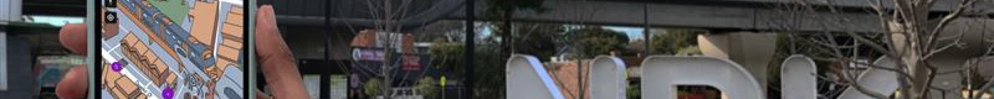 Phone with map and Noble Park in background