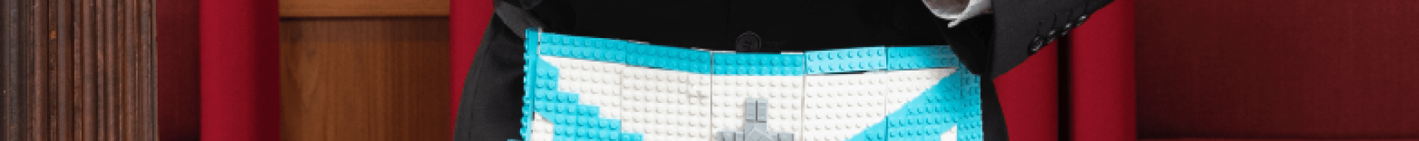 a person of colour holding a gavel made from LEGO