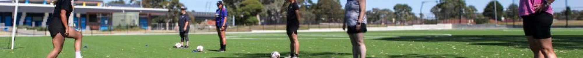 Women standing with soccer balls at their feet