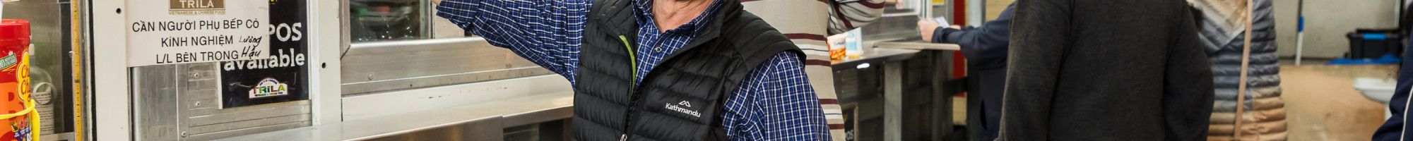 A person in front of a market stall pointing to a television.