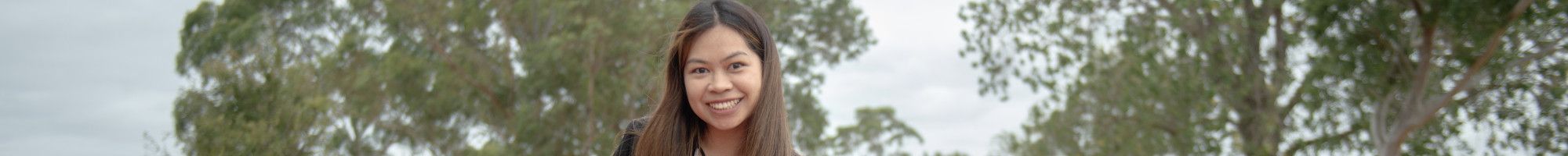Smiling woman sitting on a picnic rug while opening a wicker picnic basket