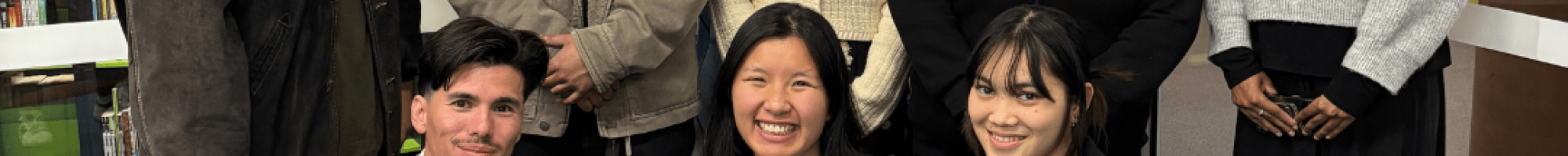A group of smiling youth some in a line behind others kneeling on the ground.
