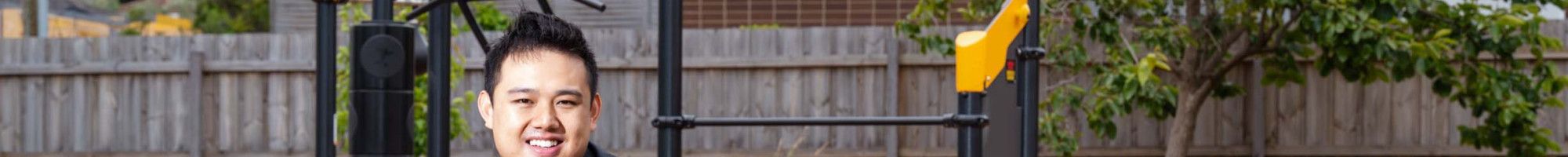 A man in a suit sits on a picnic table in front of play equipment