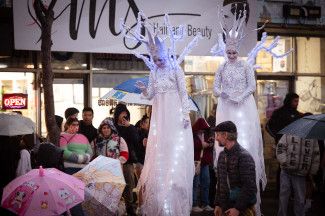 Two stilt walkers waving at attendees 