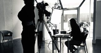 Black and white image of two people filming at an art gallery null