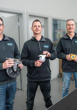 Three people standing behind a counter in a shop.